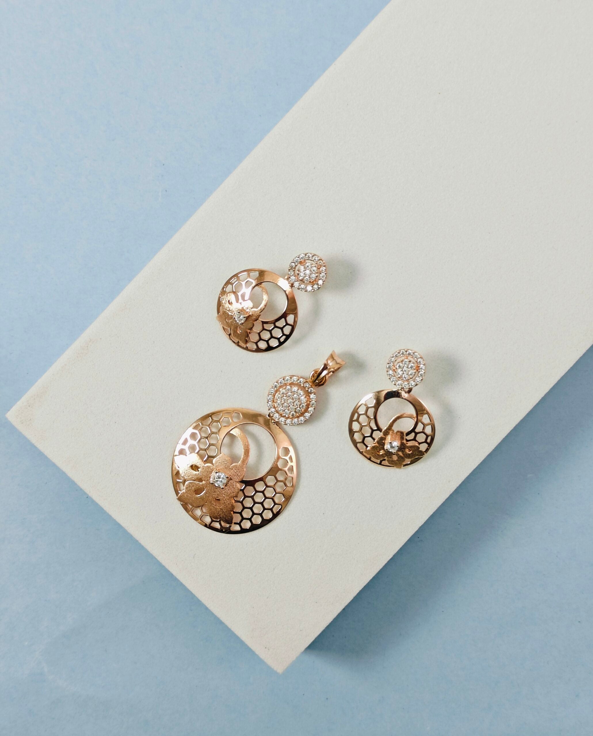 Set of gold earrings on a light beige card with a blue background